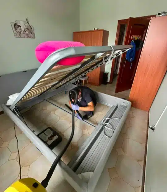 Tecnico aspira la rete e il contenitore del letto durante una disinfestazione da cimici